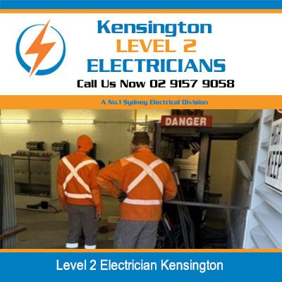 Two level 2 electricians in high-visibility orange shirts working on electrical panel in Kensington 